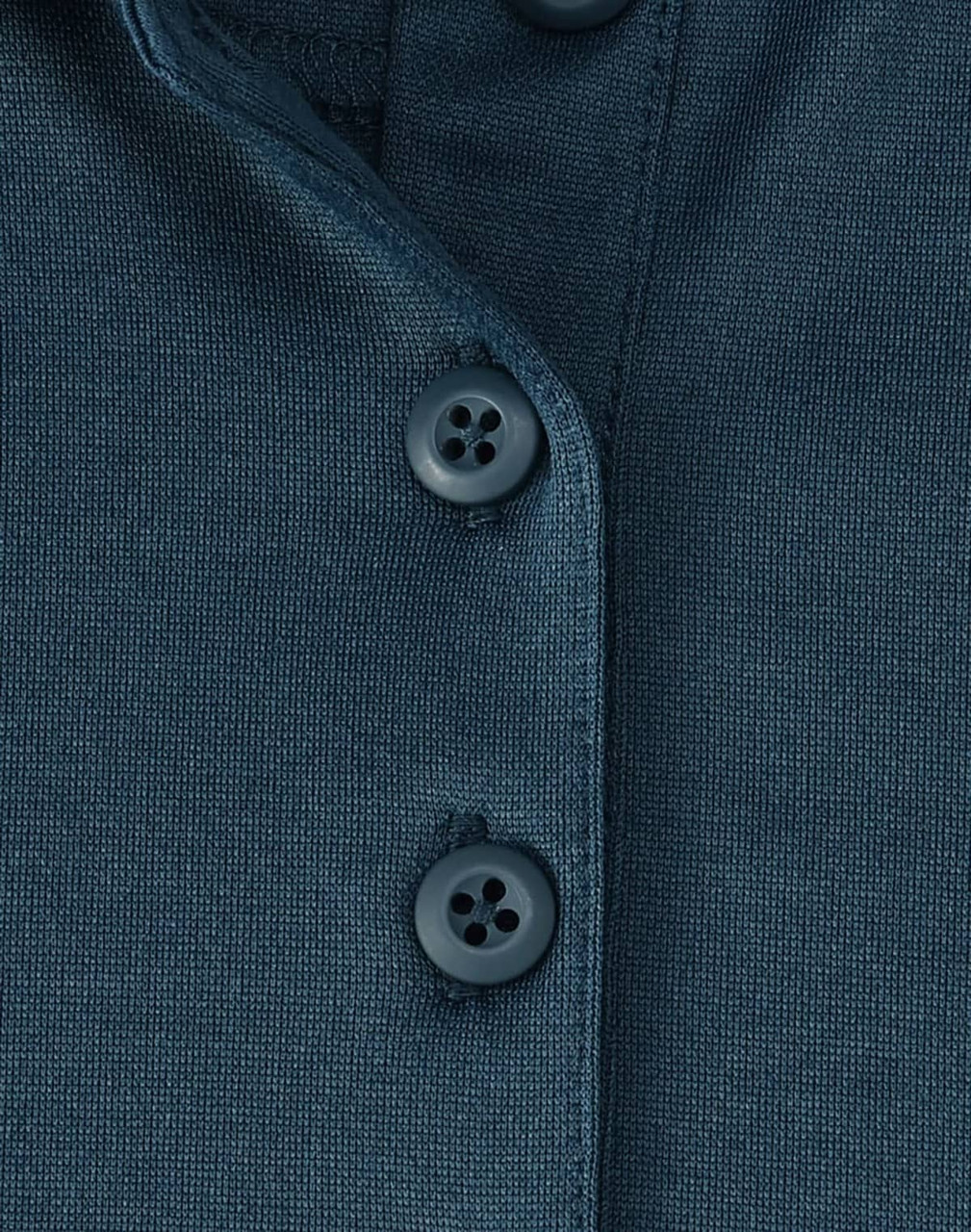 A close-up of a dark teal polo shirt featuring three buttons and a textured fabric. The shirt has a logo.
