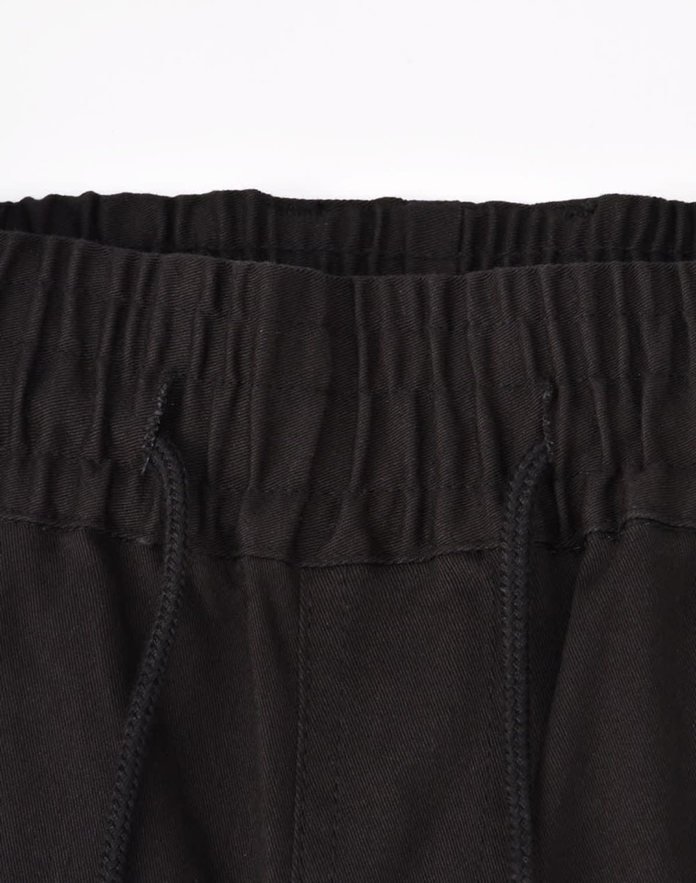 A close-up of unisex cotton stretch drill cuffed work pants in black, featuring an elastic waistband and drawstring.