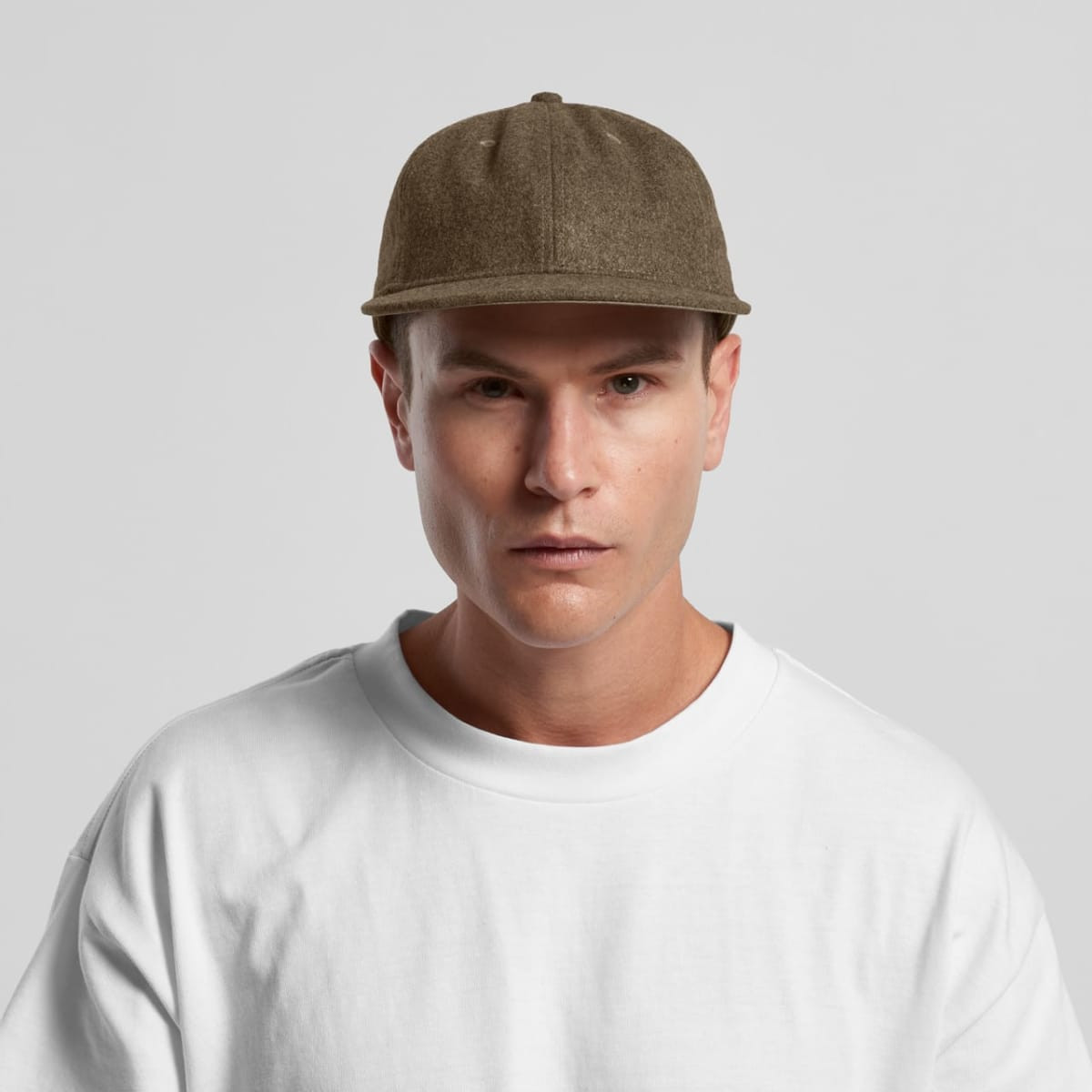 A wool cap in a brownish-green hue is worn by a model in a white t-shirt, featuring a brand logo.