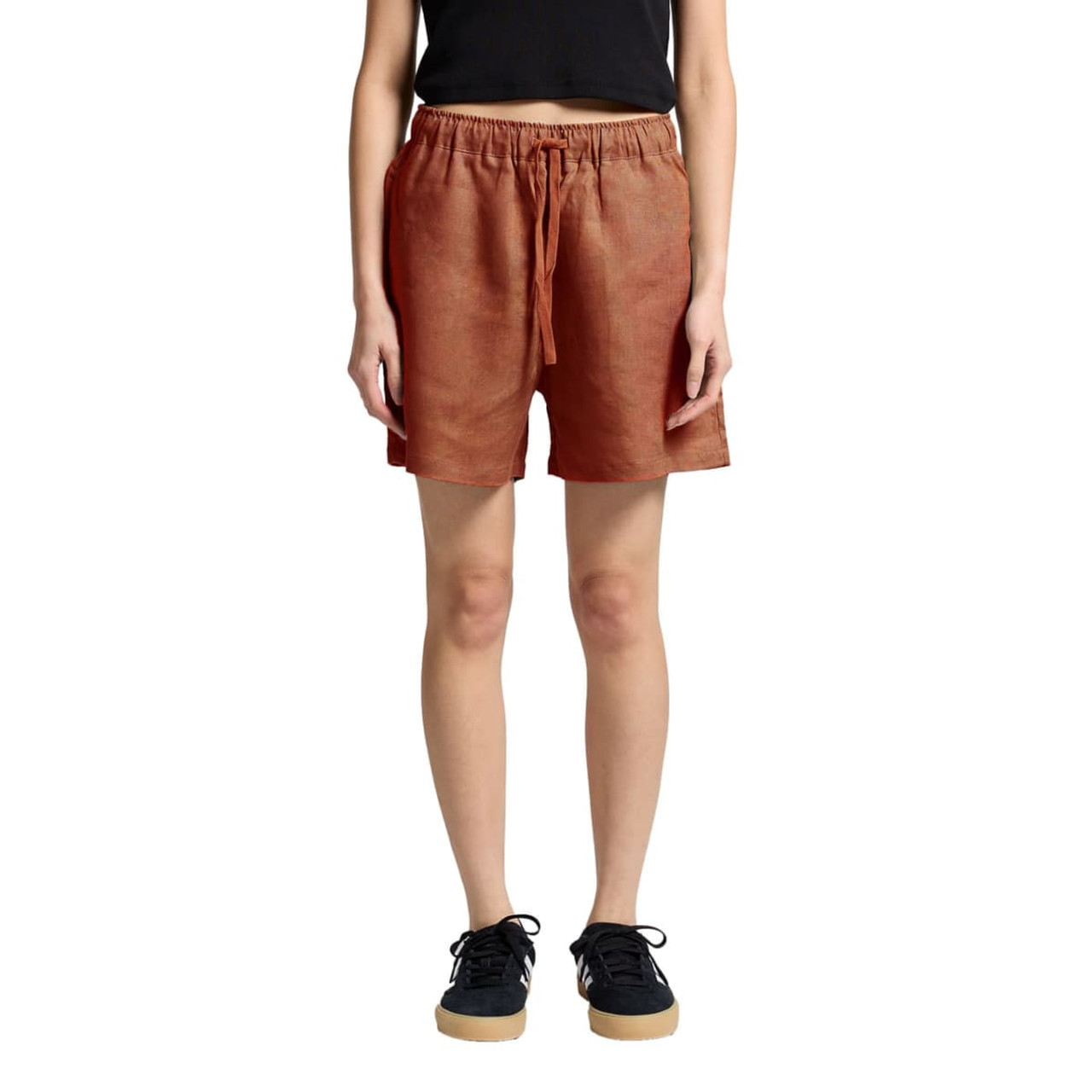 Linen dress shorts in a terracotta colour featuring an elastic waistband and side pockets, shown on a model. Linen dress shorts in a terracotta colour featuring an elastic waistband and side pockets, shown on a model.