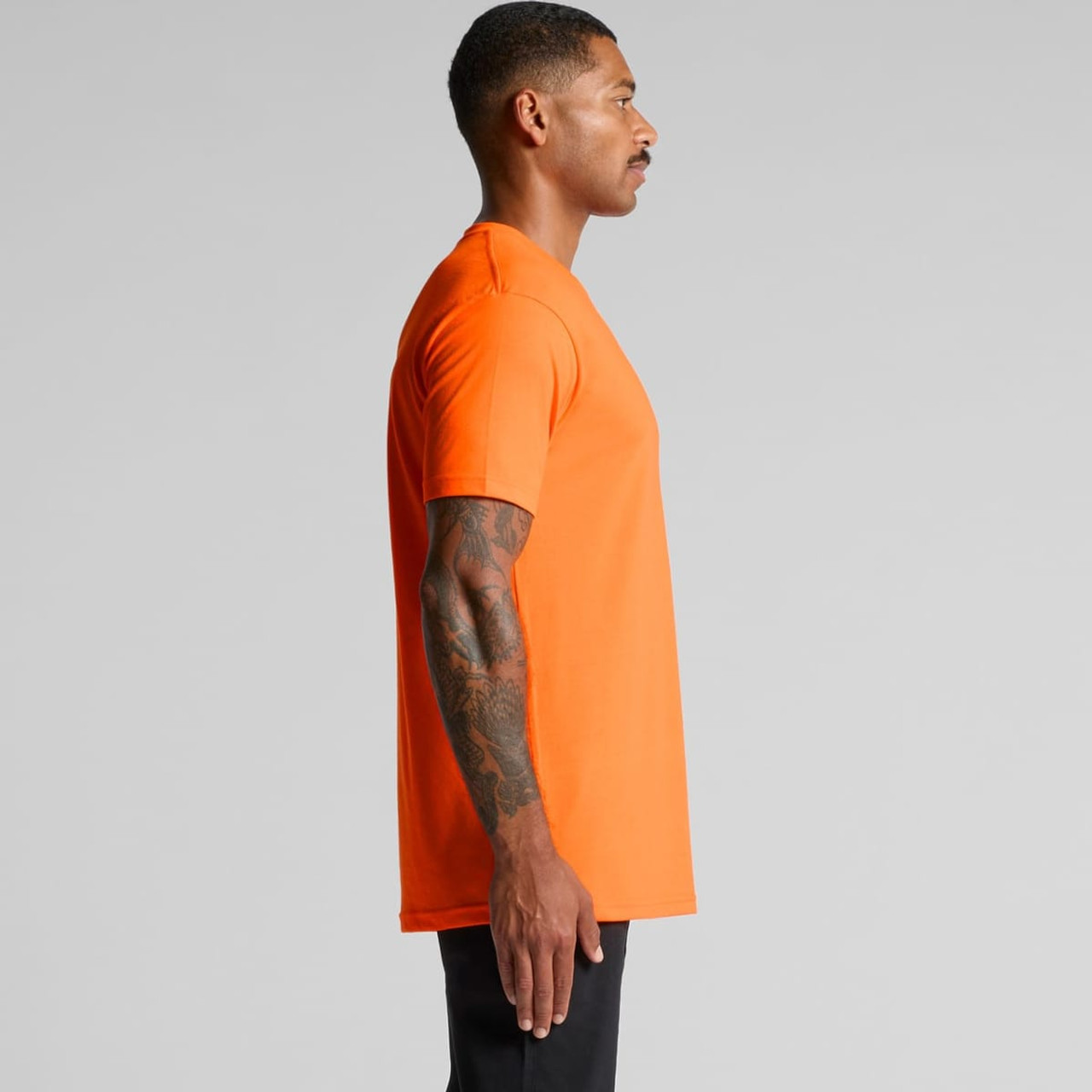 An orange work t-shirt displayed from the side, featuring a simple design and a logo on the chest. An orange work t-shirt displayed from the side, featuring a simple design and a logo on the chest.