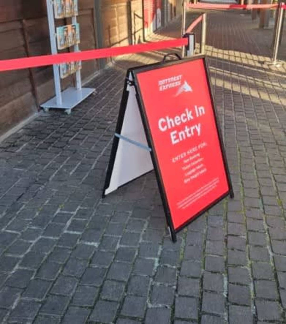 A-frame sign with a red background, featuring information for check-in entry, set on a cobblestone path.