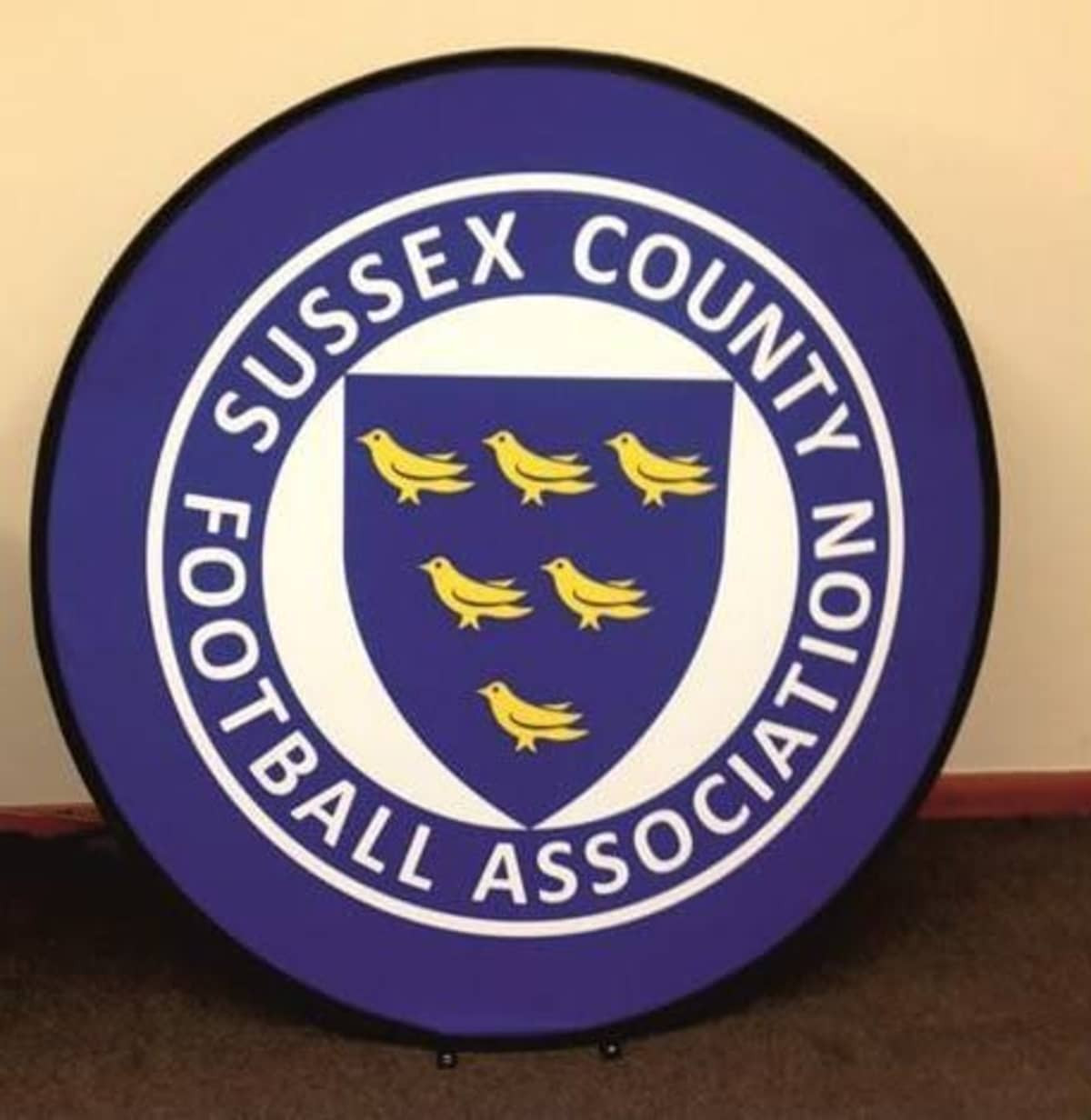 A round pop-up banner featuring a blue background with a shield and yellow birds, including a logo.