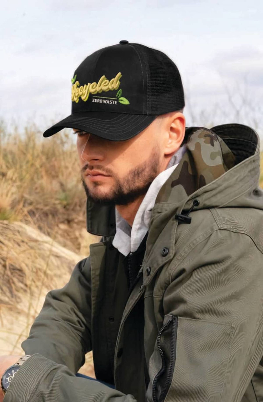 A black cap with a mesh back, featuring a logo, worn by a person in a green jacket outdoors.