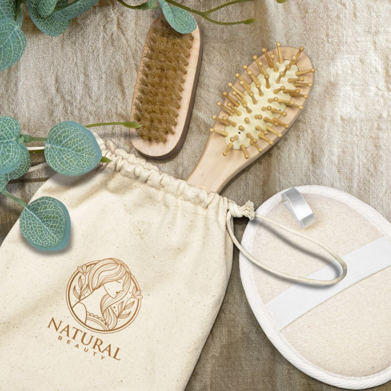 A natural beauty travel set featuring a wooden brush, exfoliating pad, and a fabric storage pouch, all in soft tones.