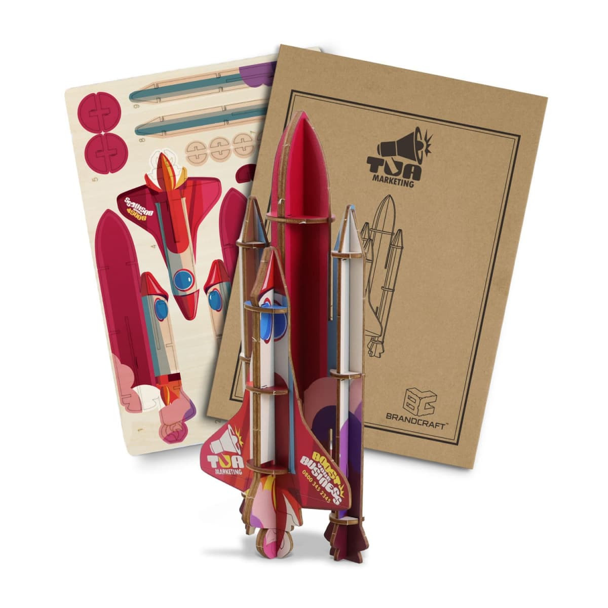 A wooden model of a rocket ship in red and white, alongside a packaging box and assembly parts.