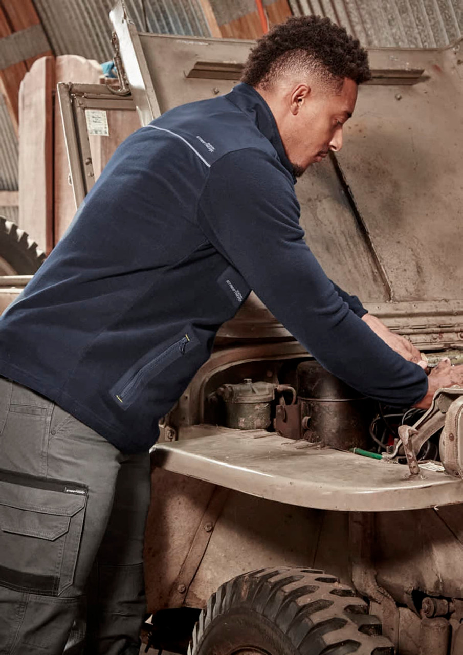 A person wearing a navy lightweight 1/4 zip polar fleece working on a vehicle under the hood, featuring a logo.