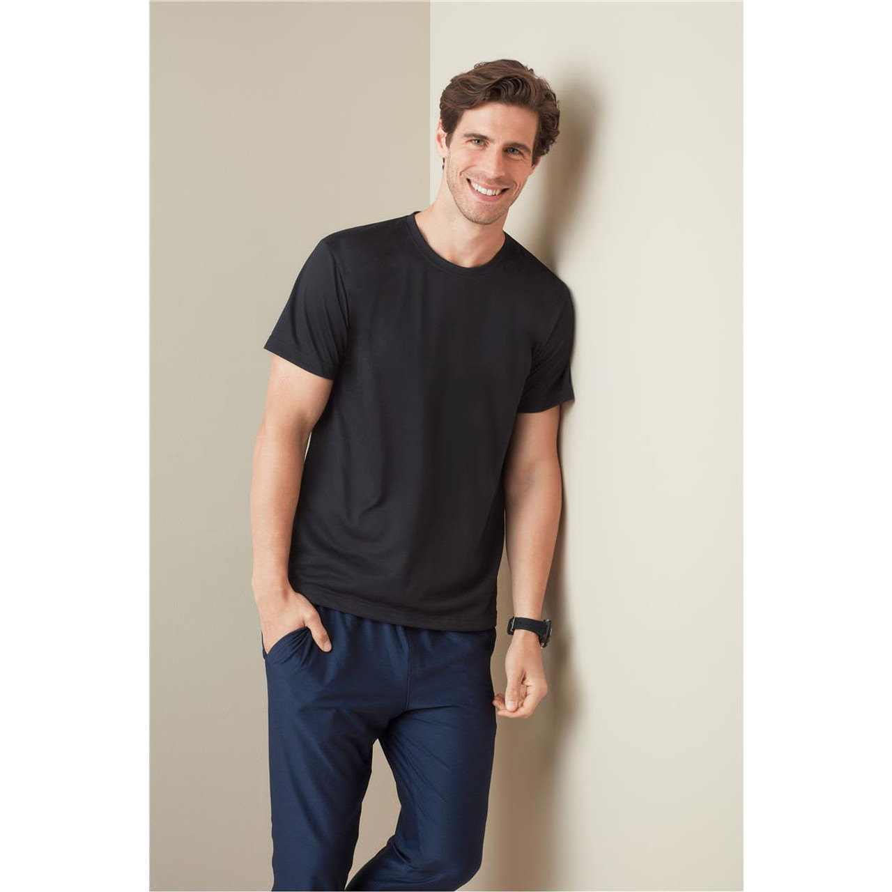 A black men's active cotton touch t-shirt, worn by a smiling man, paired with navy pants, against a light background. A black men's active cotton touch t-shirt, worn by a smiling man, paired with navy pants, against a light background.