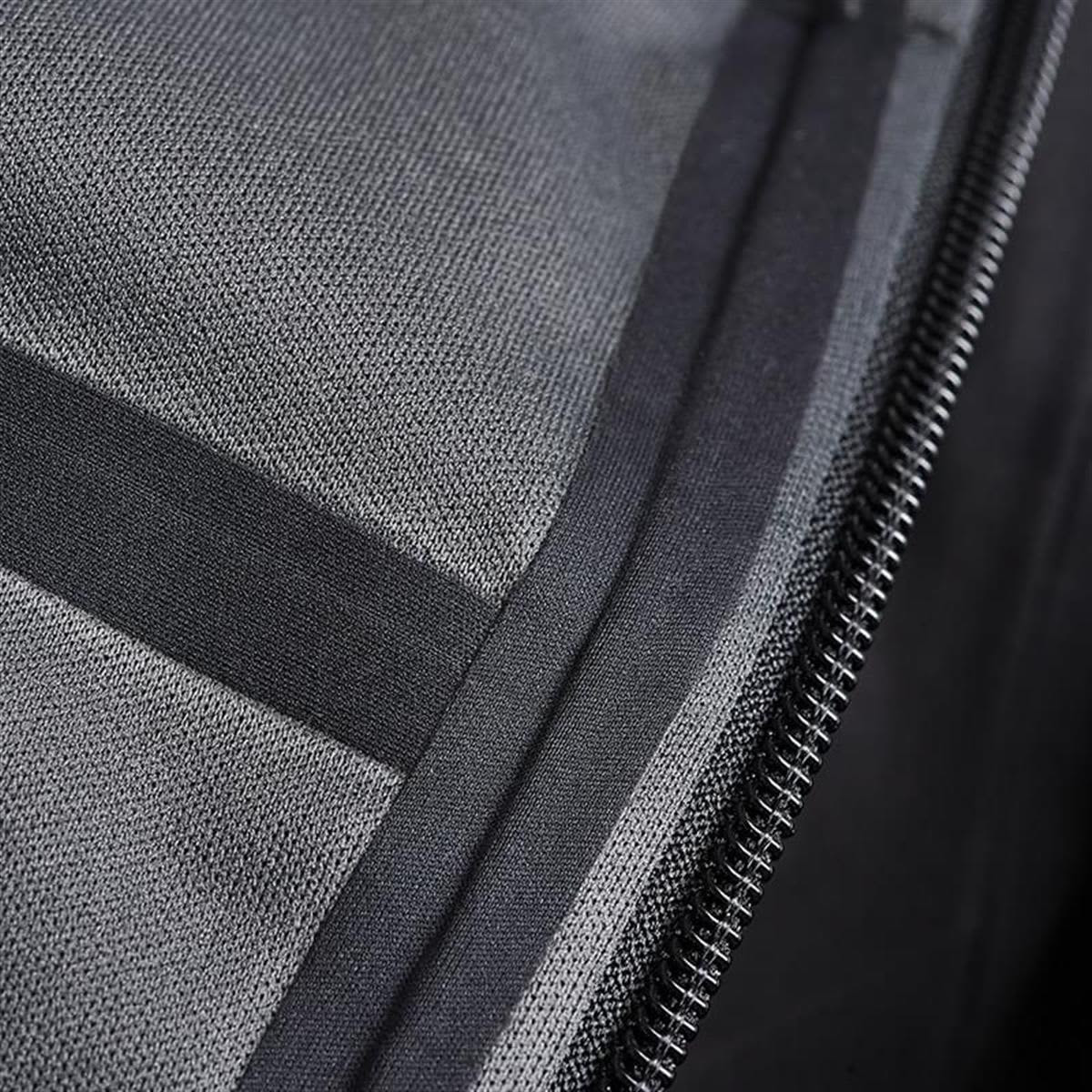 A close-up of a black softshell jacket, showcasing its fabric texture and zipper detail. It features a logo on the fabric.