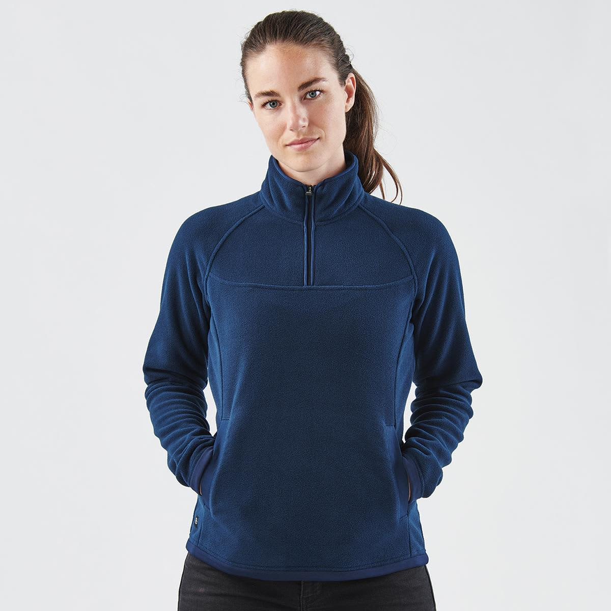 A navy blue women's fleece jumper with a 1/4 zip and a logo on the side. The model is posing with hands in pockets.