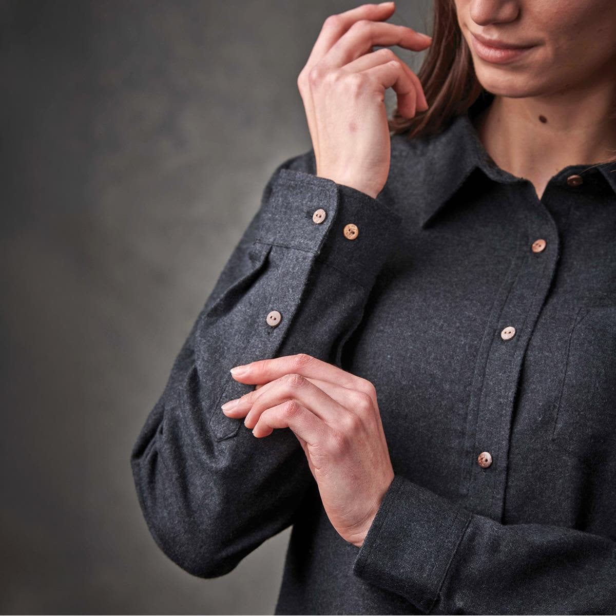 A grey women's button-up shirt with a collar and rolled sleeves, featuring buttons on the cuffs.