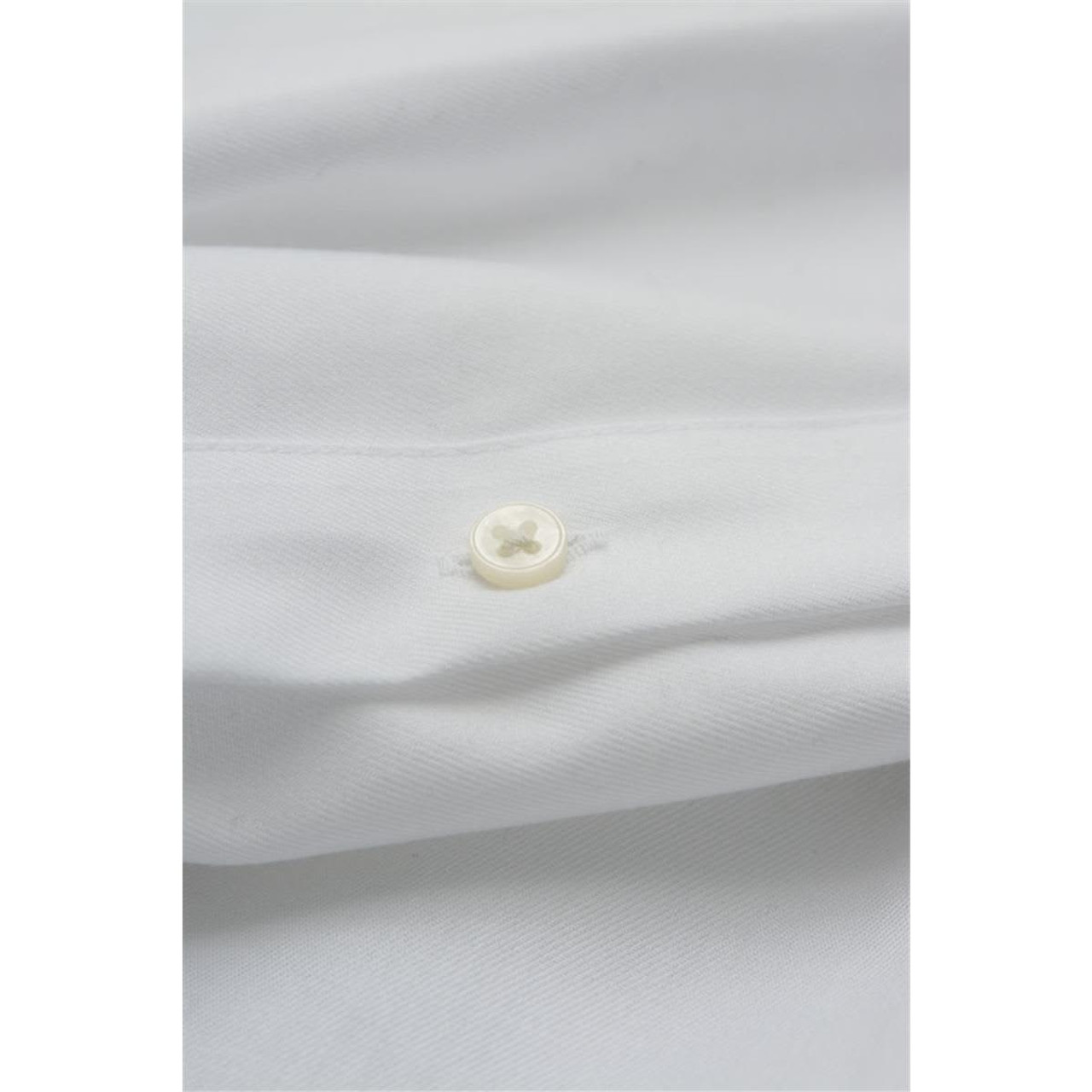 A black button on a folded black shirt, showcasing the fabric texture and stitching details. The shirt has a logo. A black button on a folded black shirt, showcasing the fabric texture and stitching details. The shirt has a logo.