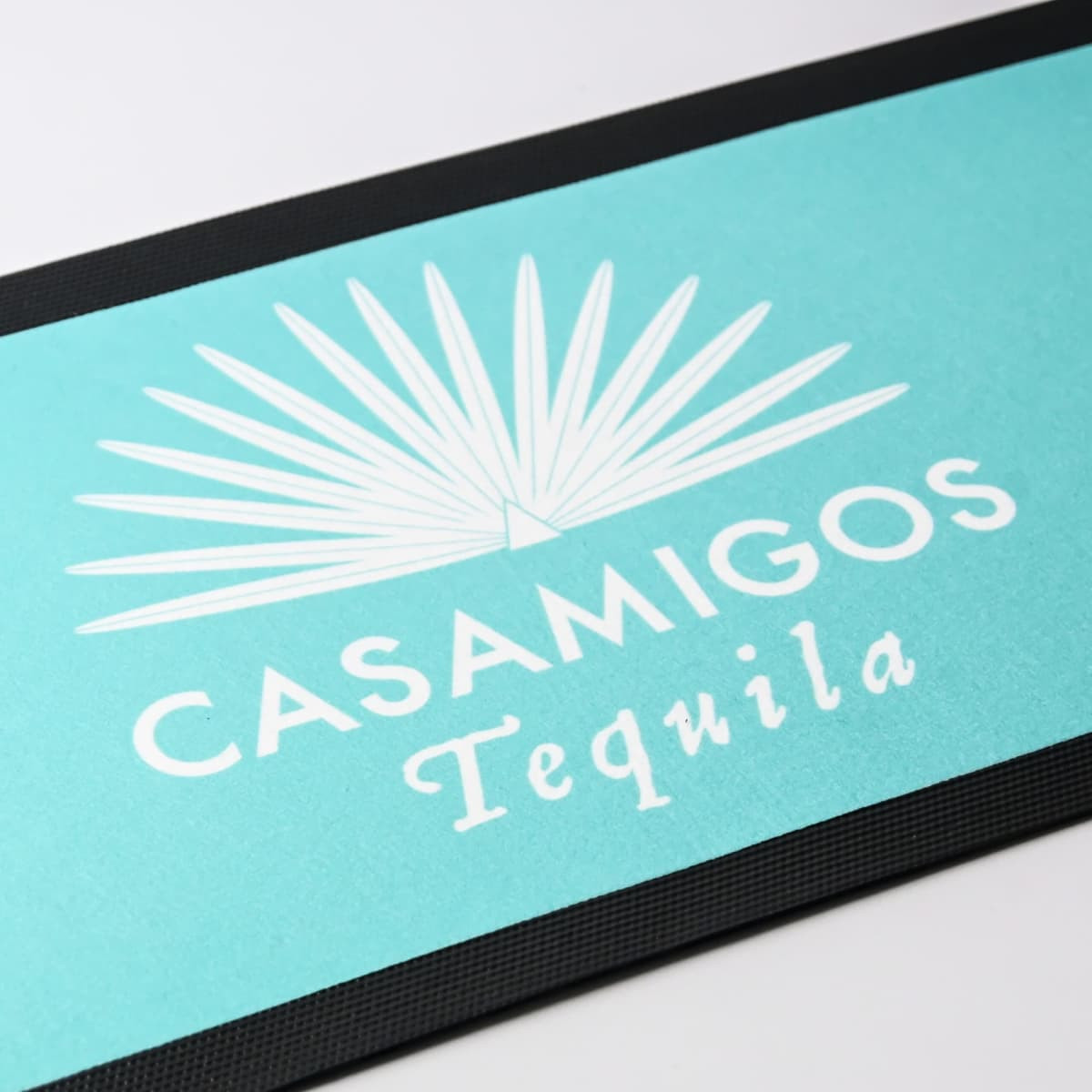 A turquoise bar runner featuring a palm leaf design and a logo, set against a black trim.