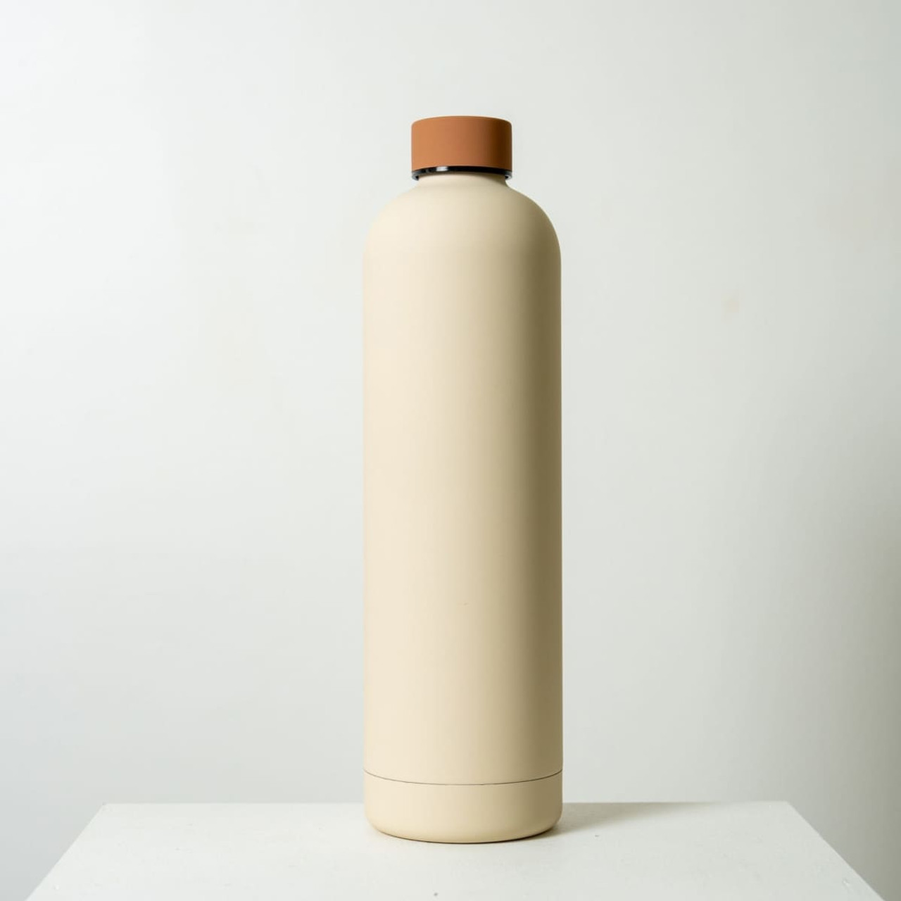 A drink bottle in a cream colour with a brown lid, featuring a minimalist design and a small logo.
