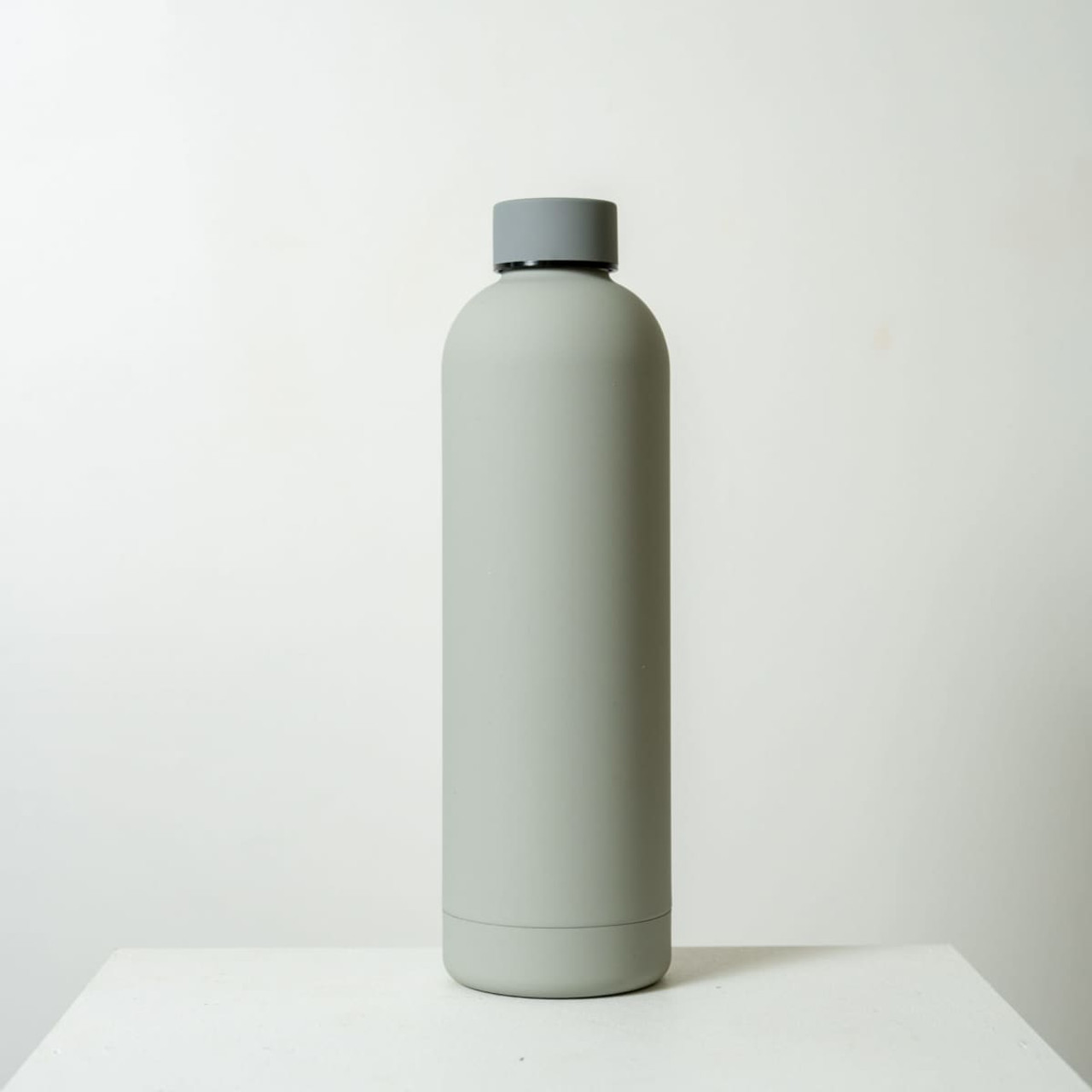 A drink bottle in matte grey with a screw-top lid and a minimalist design. It features a logo on the side.