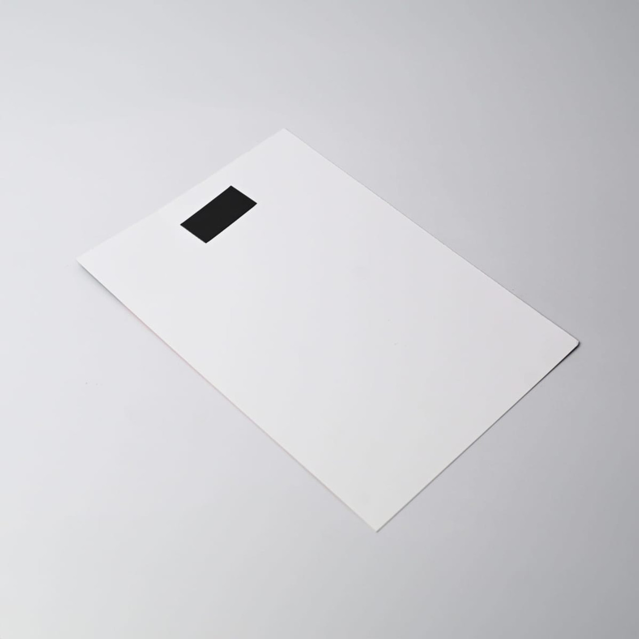 A flat, white magnetic calendar with a black tab at the top. The design is simple and minimalistic.