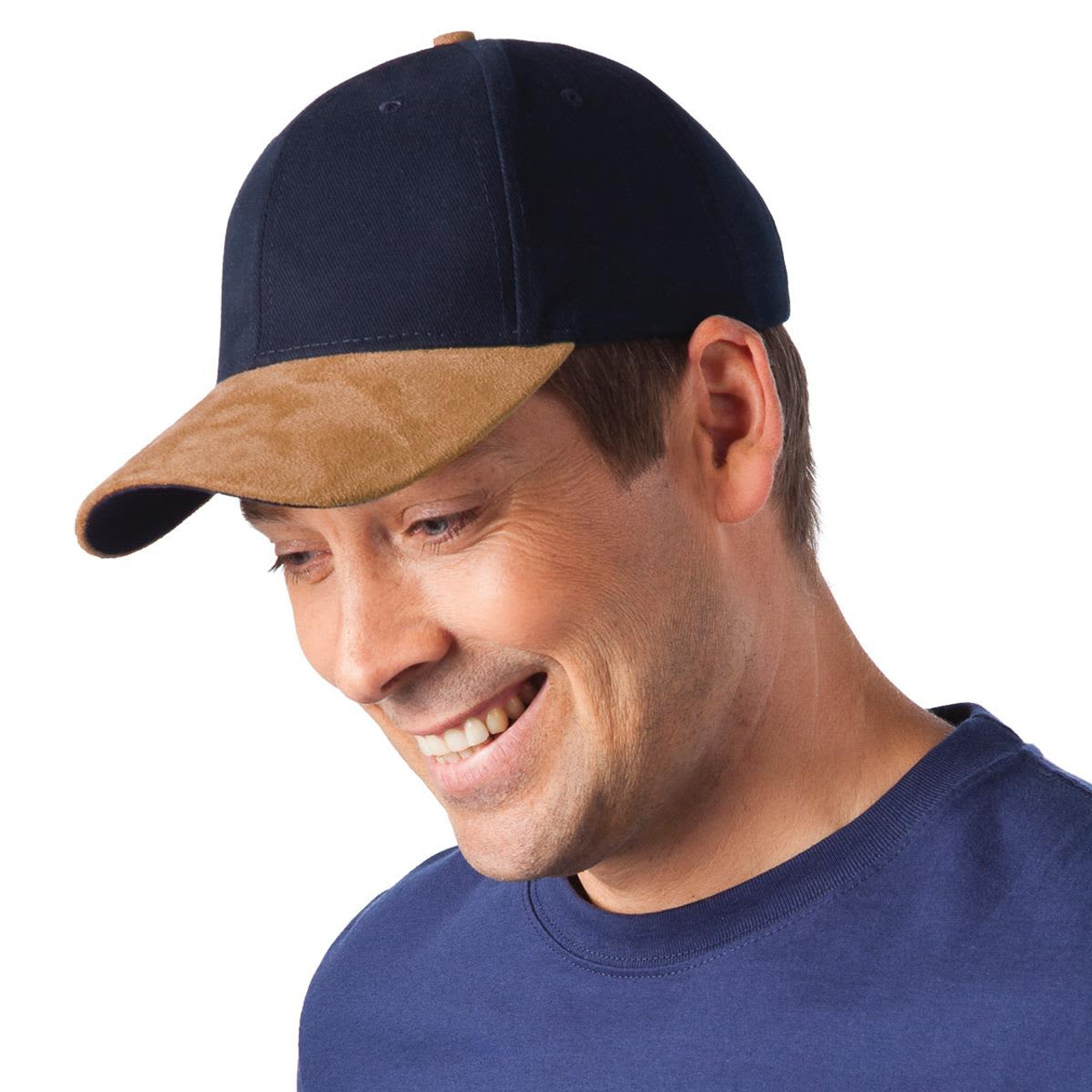 A navy and tan sueded peak cap is worn by a smiling man, featuring a logo on the front.