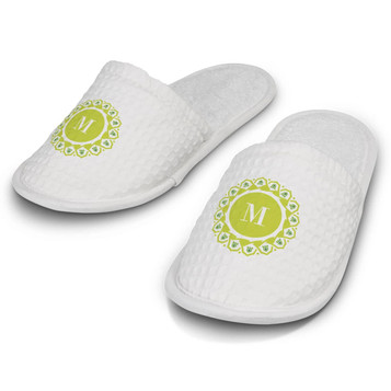 White waffle slippers with a green circular design and a logo on the front. Soft, textured fabric with a cushioned sole.