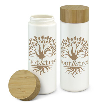 A drink bottle features a white ceramic body and a bamboo lid, adorned with a tree logo.