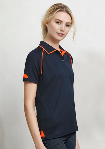 A navy blue women's polo shirt featuring orange accents on the collar and sleeves, with branding. A navy blue women's polo shirt featuring orange accents on the collar and sleeves, with branding.