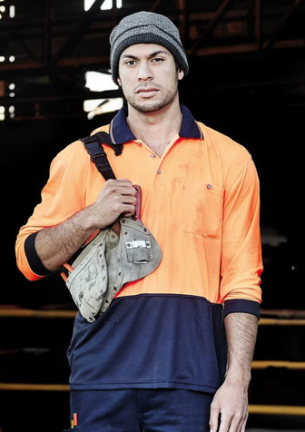 A man wearing an orange and navy blue long sleeve polo shirt, holding a work bag and wearing a grey beanie.