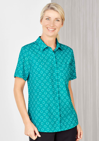 A short sleeve shirt in teal featuring a white daisy print and a button-up front. It has a single chest pocket. A short sleeve shirt in teal featuring a white daisy print and a button-up front. It has a single chest pocket.