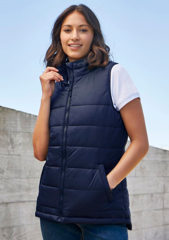 A navy women's alpine vest with a zip front, styled with a white t-shirt underneath, and featuring side pockets. A navy women's alpine vest with a zip front, styled with a white t-shirt underneath, and featuring side pockets.