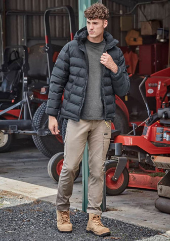 A black hooded puffer jacket is worn over a grey shirt, paired with beige pants and tan boots in an outdoor setting. A black hooded puffer jacket is worn over a grey shirt, paired with beige pants and tan boots in an outdoor setting.