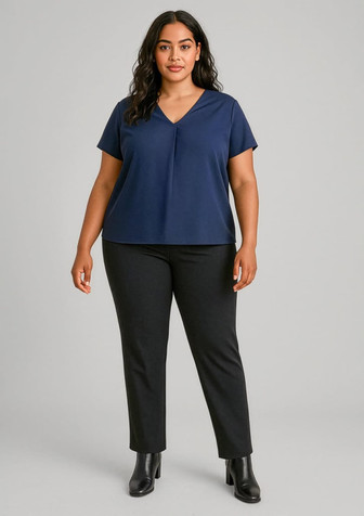 A model wearing a navy top and black mid-rise pull-on pants, with sleek black boots. The outfit features a subtle logo.