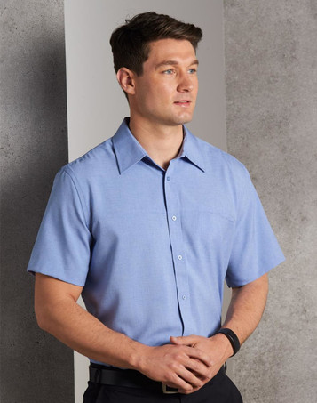 A short-sleeve men's shirt in light blue with a button-down front and a chest pocket, featuring a logo.