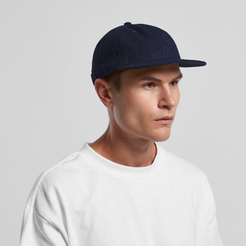 A navy wool cap with a flat brim, worn by a model in a white shirt. The cap features a logo. A navy wool cap with a flat brim, worn by a model in a white shirt. The cap features a logo.
