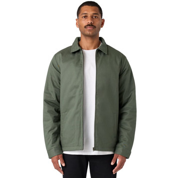 A man wearing a green service jacket over a white t-shirt, standing with a neutral expression. The jacket has a logo.