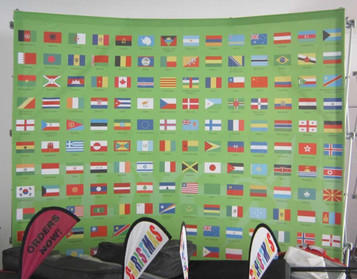 A curved media wall featuring a vibrant green background with numerous flags from various countries.