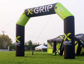 An inflatable air arch, 7m tall, in black and bright green with branding, set on a grassy field.