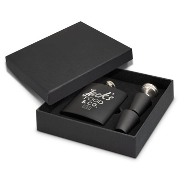 A black hip flask gift set with two metal pourers, presented in a matching black box. It features branding. A black hip flask gift set with two metal pourers, presented in a matching black box. It features branding.