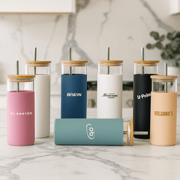 A collection of colourful plastic tumblers with bamboo lids and straws in various shades, featuring different logos.