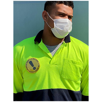 A person wearing a high-visibility yellow and navy polo shirt with a badge and a white face mask. A person wearing a high-visibility yellow and navy polo shirt with a badge and a white face mask.