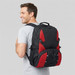 A man wearing a black and red outdoor backpack, showcasing mesh side panels and adjustable straps.