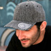 A grey cap with a mid visor and a logo on the brim, featuring a textured fabric design.