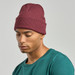 A maroon beanie worn by a person in a teal shirt, featuring a logo on the front.