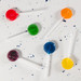 Assorted lollipops in red, green, orange, blue, yellow, and purple on a textured surface, featuring white sticks. Assorted lollipops in red, green, orange, blue, yellow, and purple on a textured surface, featuring white sticks.
