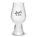 A clear glass beer glass with a wide bowl and a tapered base, featuring a logo. A clear glass beer glass with a wide bowl and a tapered base, featuring a logo.