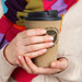 A drink bottle with a double wall design, featuring a beige exterior and a black lid, held by a person.