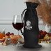 A black jute wine drawstring bag stands next to a glass of red wine, surrounded by food items and a decorative background.