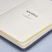 A blue notebook with a hard cover, featuring lined pages and a logo on the inside cover.