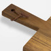 A wooden chopping board with a natural finish and a leather tie attached for hanging.