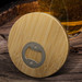 A drink bottle opener coaster made of natural bamboo with a round design and metallic opener. A drink bottle opener coaster made of natural bamboo with a round design and metallic opener.