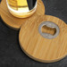 A drink bottle rests on two round bamboo coasters, each featuring a metal bottle opener in the centre. A drink bottle rests on two round bamboo coasters, each featuring a metal bottle opener in the centre.