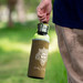 A drink bottle with a cork sleeve, featuring a metal lid, held by a person in a natural setting. A drink bottle with a cork sleeve, featuring a metal lid, held by a person in a natural setting.