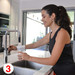 A drink bottle with a clear design is being filled with water at a kitchen sink. The setting features modern appliances. A drink bottle with a clear design is being filled with water at a kitchen sink. The setting features modern appliances.